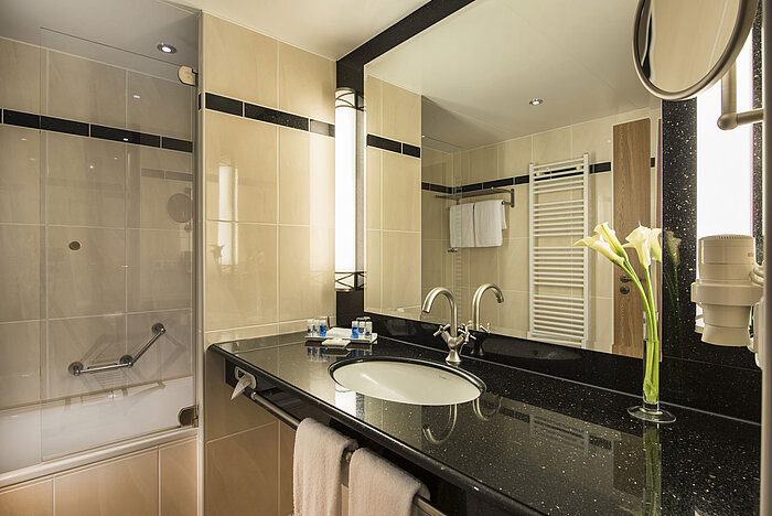 Modernes Badezimmer mit Waschbecken, Spiegel, Badewanne und eleganten Details im Maritim Hotel Dresden.