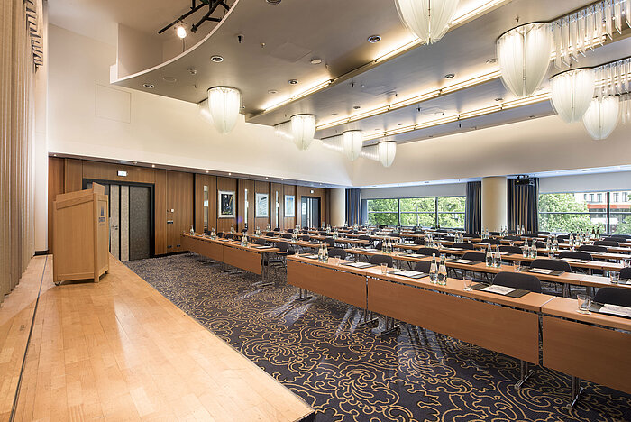 Konferenzraum mit Bühne und Panoramafenstern im Maritim Hotel Frankfurt. Reihenbestuhlung und modernes Design.