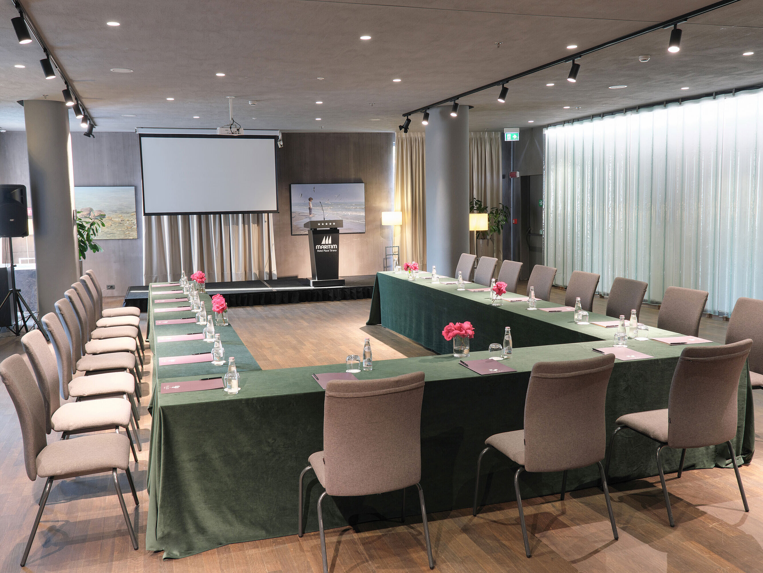 Stilvoller Raum im Maritim Hotel Plaza Tirana mit U-Bestuhlung, Leinwand und frischen Blumen