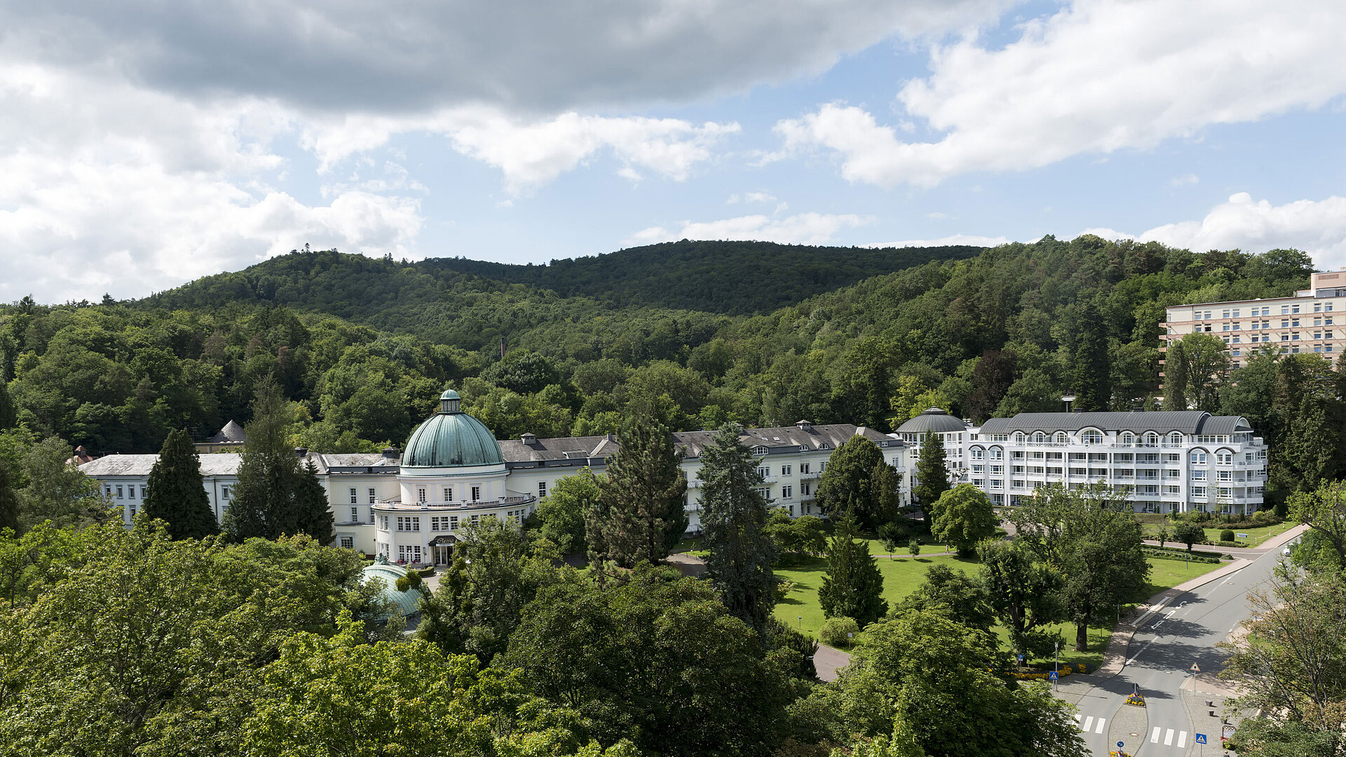Blick auf das Maritim Hotel Bad Wildungen, umgeben von Bäumen und der grünen Landschaft des Kurparks.