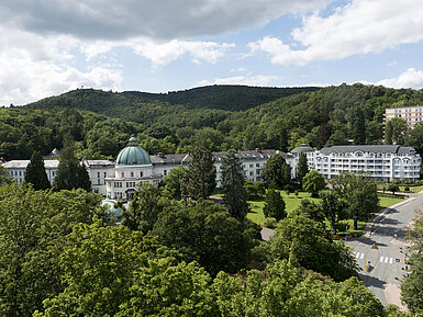 Außenansicht Blick auf das Maritim Hotel Bad Wildungen, umgeben von Bäumen und der grünen Landschaft des Kurparks.