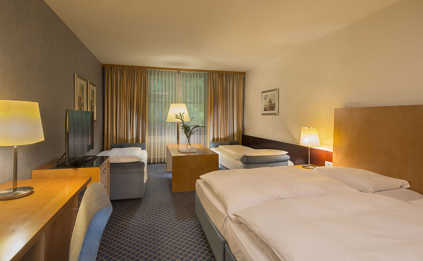 Geräumiges Familienzimmer im Maritim Hotel Fulda mit vier Betten, Schreibtisch und gemütlicher Atmosphäre.