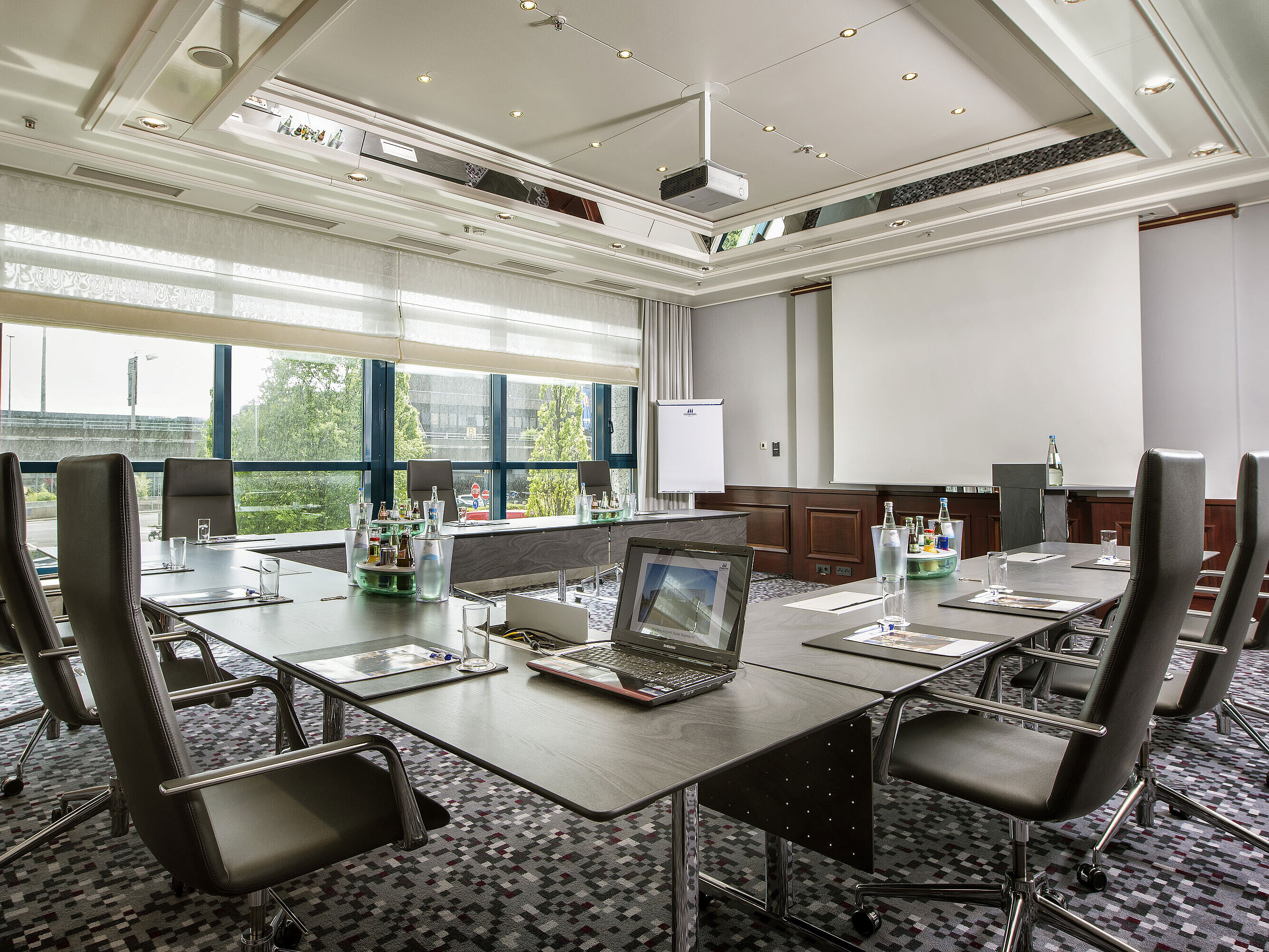 Heller Tagungsraum mit großem Konferenztisch, Ledersesseln und moderner Technik im Maritim Hotel Hannover.
