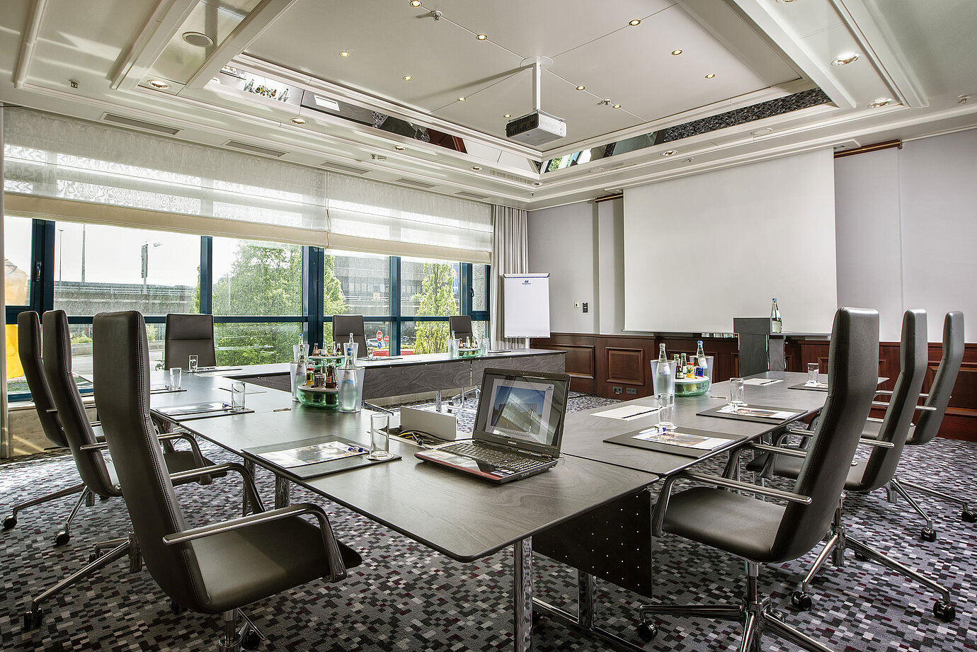 Heller Tagungsraum mit großem Konferenztisch, Ledersesseln und moderner Technik im Maritim Hotel Hannover.