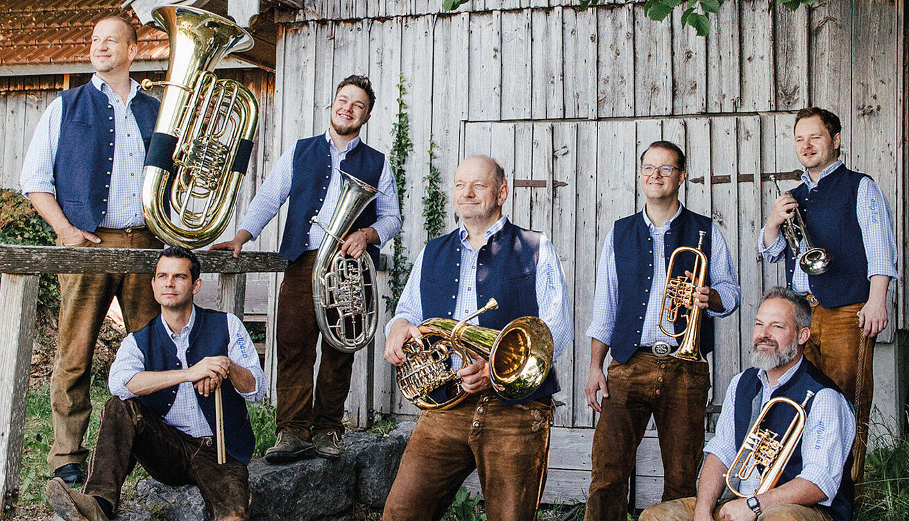Musikgruppe Allgäu 6 in traditioneller Tracht mit Instrumenten in alpiner Umgebung