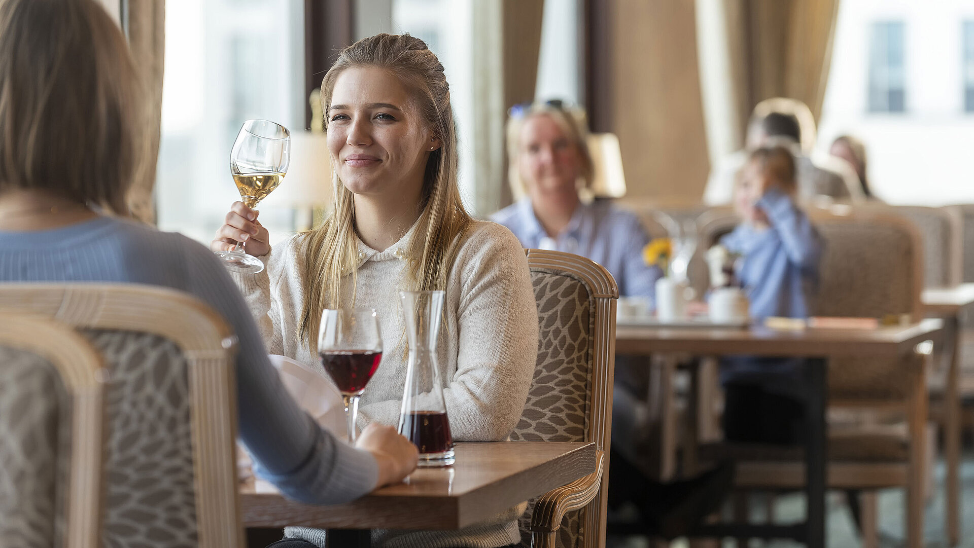 Ostseerestaurant Frau mit Weißwein genießt das stilvolle Ambiente im Restaurant des Maritim Hotel Travemünde