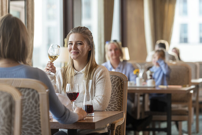 Frau mit Weißwein genießt das stilvolle Ambiente im Restaurant des Maritim Hotel Travemünde