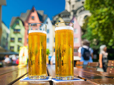 Zwei Gläser Bier auf Tisch im Biergarten vor historischer Altstadt