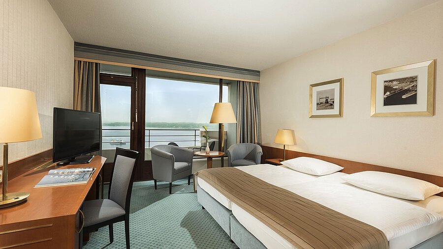 Superior Zimmer im Maritim Hotel Kiel mit Schreibtisch, Sitzbereich, großem Doppelbett und Balkon mit Blick auf die Förde.