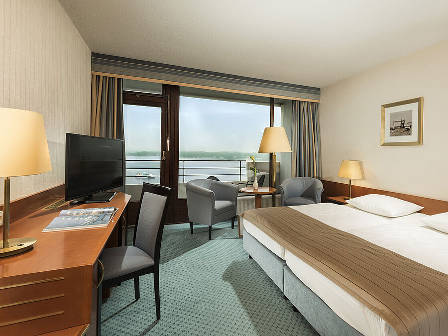 Superior Zimmer im Maritim Hotel Kiel mit Schreibtisch, Sitzbereich, großem Doppelbett und Balkon mit Blick auf die Förde.