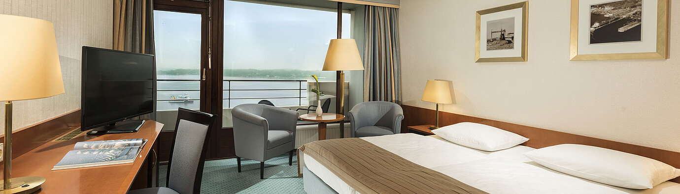 Superior Zimmer im Maritim Hotel Kiel mit Schreibtisch, Sitzbereich, großem Doppelbett und Balkon mit Blick auf die Förde.