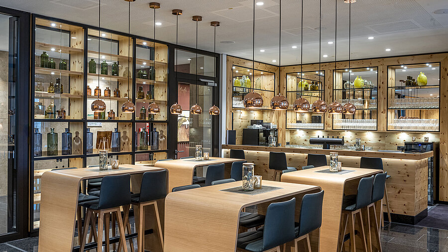  Elegante Bar mit Holzdekor, stilvollen Pendelleuchten und hohen Sitzgelegenheiten im Maritim Hotel Ingolstadt.