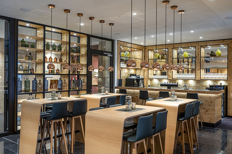  Elegante Bar mit Holzdekor, stilvollen Pendelleuchten und hohen Sitzgelegenheiten im Maritim Hotel Ingolstadt.