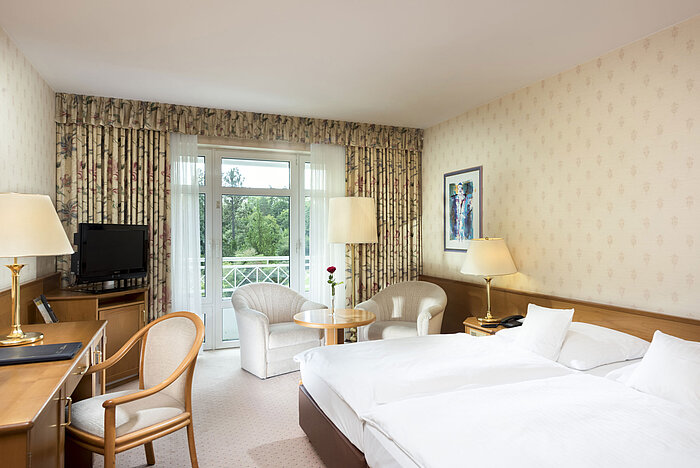 Helles Doppelzimmer mit Balkonblick und Sitzecke im Maritim Hotel Bad Wildungen