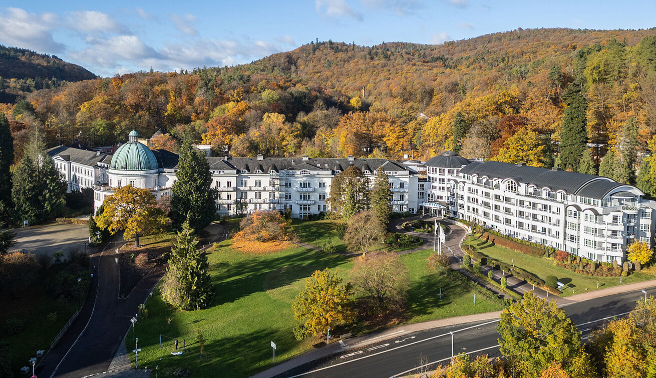Aussenansicht Außenansicht des Maritim Hotel Bad Wildungen mit Park, Bäumen und herbstlichem Wald im Hintergrund.