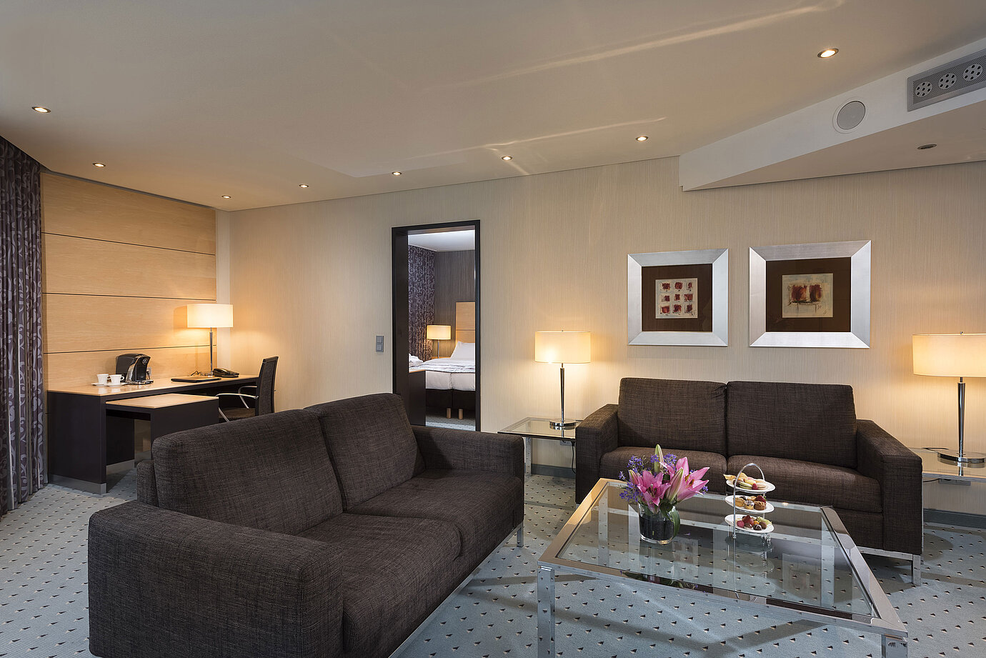 Junior Suite im Maritim Hotel Düsseldorf mit separatem Wohnbereich, zwei Sofas, Schreibtisch, Blumen und modernem Design.