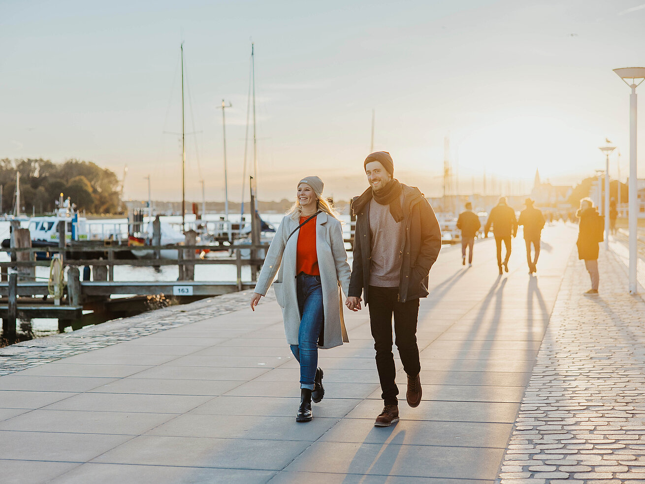 Zwei Personen spazieren an der Strandpromenade in Travemünde bei Sonnenuntergang