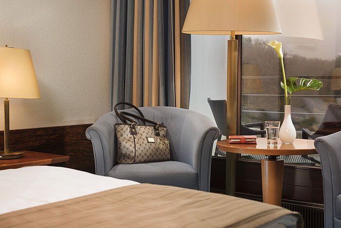 Classic Zimmer im Maritim Hotel Kiel mit gemütlicher Sitzecke, Tischlampe und stilvollem Dekor, ideal für entspannte Momente.