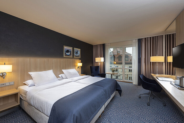 Elegantes Superior Zimmer im Maritim Hotel Würzburg mit großem Doppelbett und Ausblick auf historische Dächer