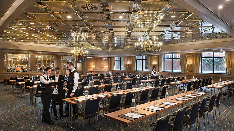 Zwei Mitarbeitende bereiten einen Konferenzraum mit Reihenbestuhlung im Maritim Hotel Stuttgart vor
