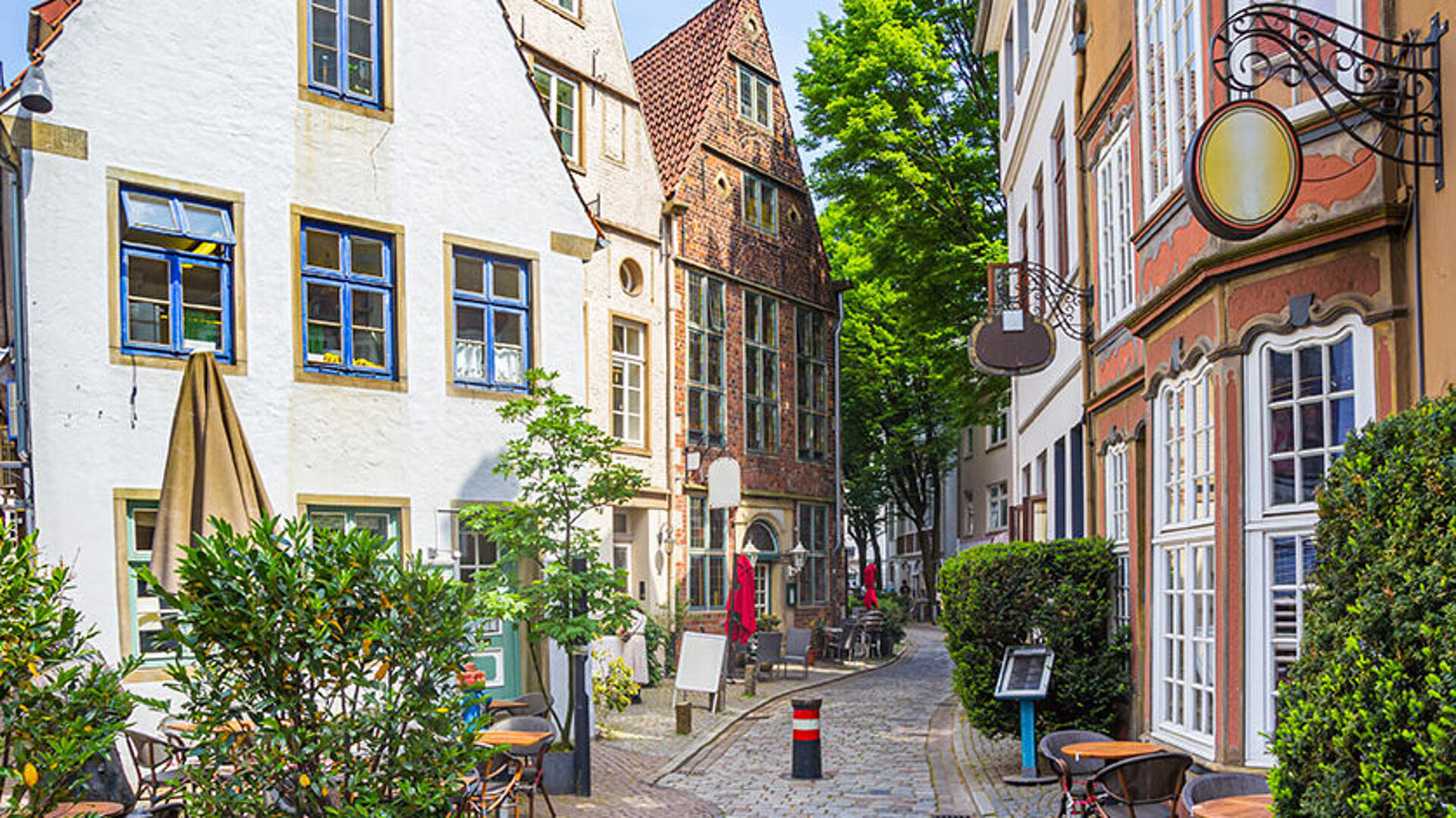 Historische Gasse im Schnoorviertel in Bremen mit alten Häusern, Kopfsteinpflaster und grüner Bepflanzung