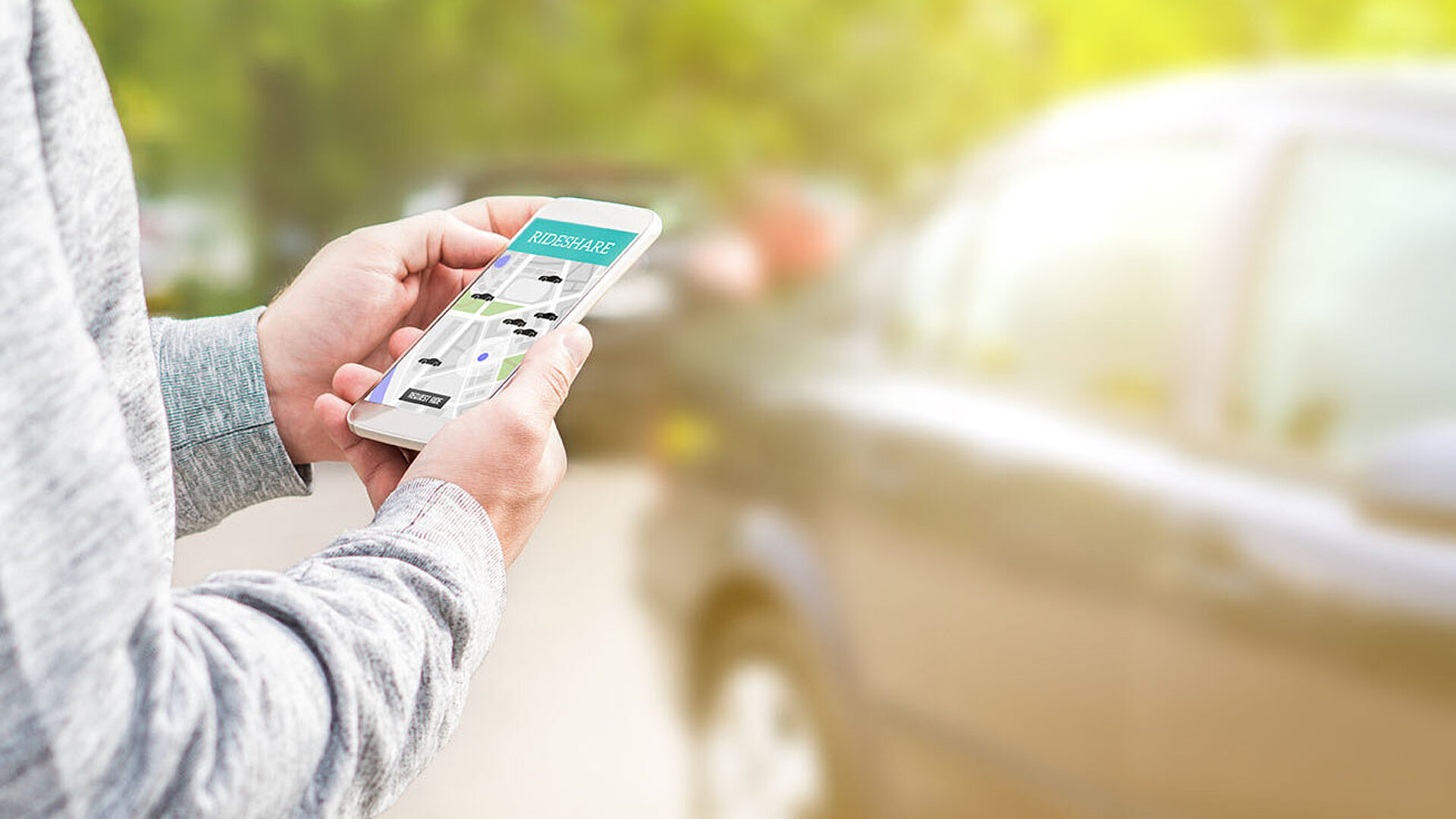 Person hält Smartphone mit Rideshare-App zur Buchung einer Mitfahrgelegenheit