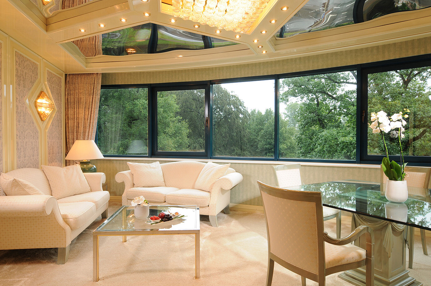 Luxuriöse Suite im Maritim Bremen mit eleganter Sitzecke, Glas-Esstisch und großem Panoramafenster mit Blick ins Grüne