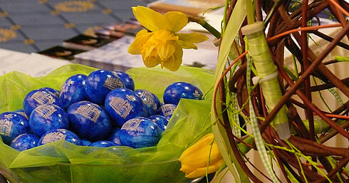 Osterdekoration im Maritim Hotel Dresden mit blauen Schokoladeneiern, Narzissen und Tulpen auf grünem Tischdekor.