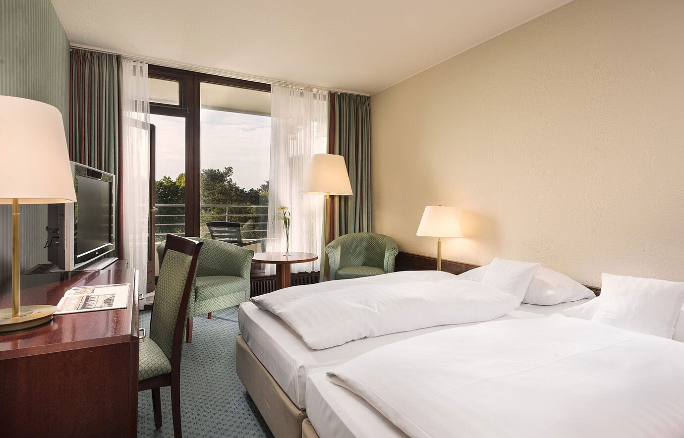Doppelzimmer mit Balkon, Sesseln und Schreibtisch im Maritim Hotel Bad Salzuflen