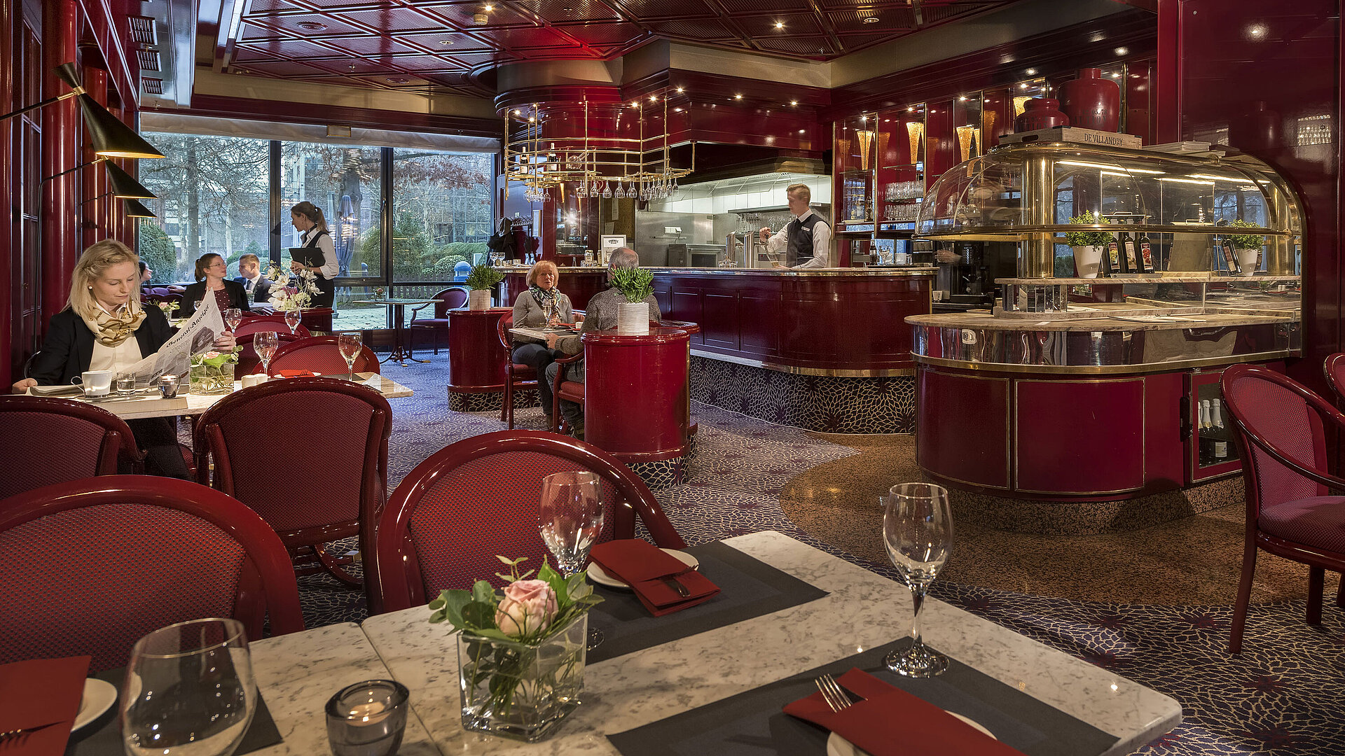 Das Bild zeigt das gemütliche Café "Brasserie" im Maritim Hotel Bonn mit roter Einrichtung und entspanntem Ambiente.