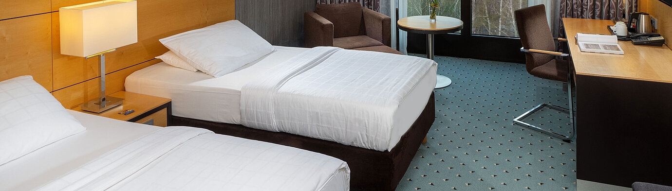 Classic Zimmer im Maritim Hotel Düsseldorf mit zwei Einzelbetten, Schreibtisch,Sessel und Fenster mit Blick auf den Flughafen