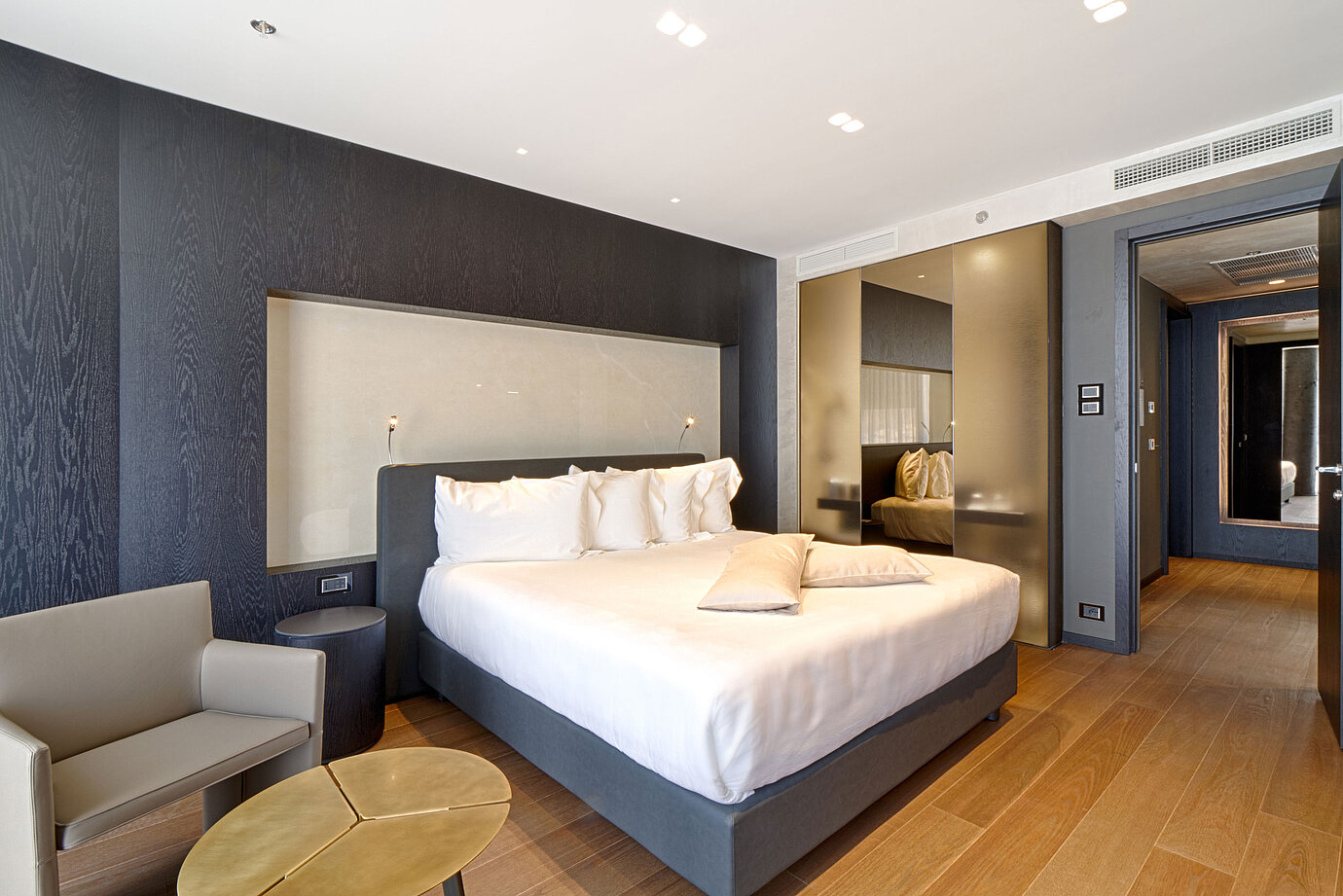 Modernes Hotelzimmer mit Kingsize-Bett, heller Wandnische und Holzfußboden im Maritim Hotel Plaza Tirana