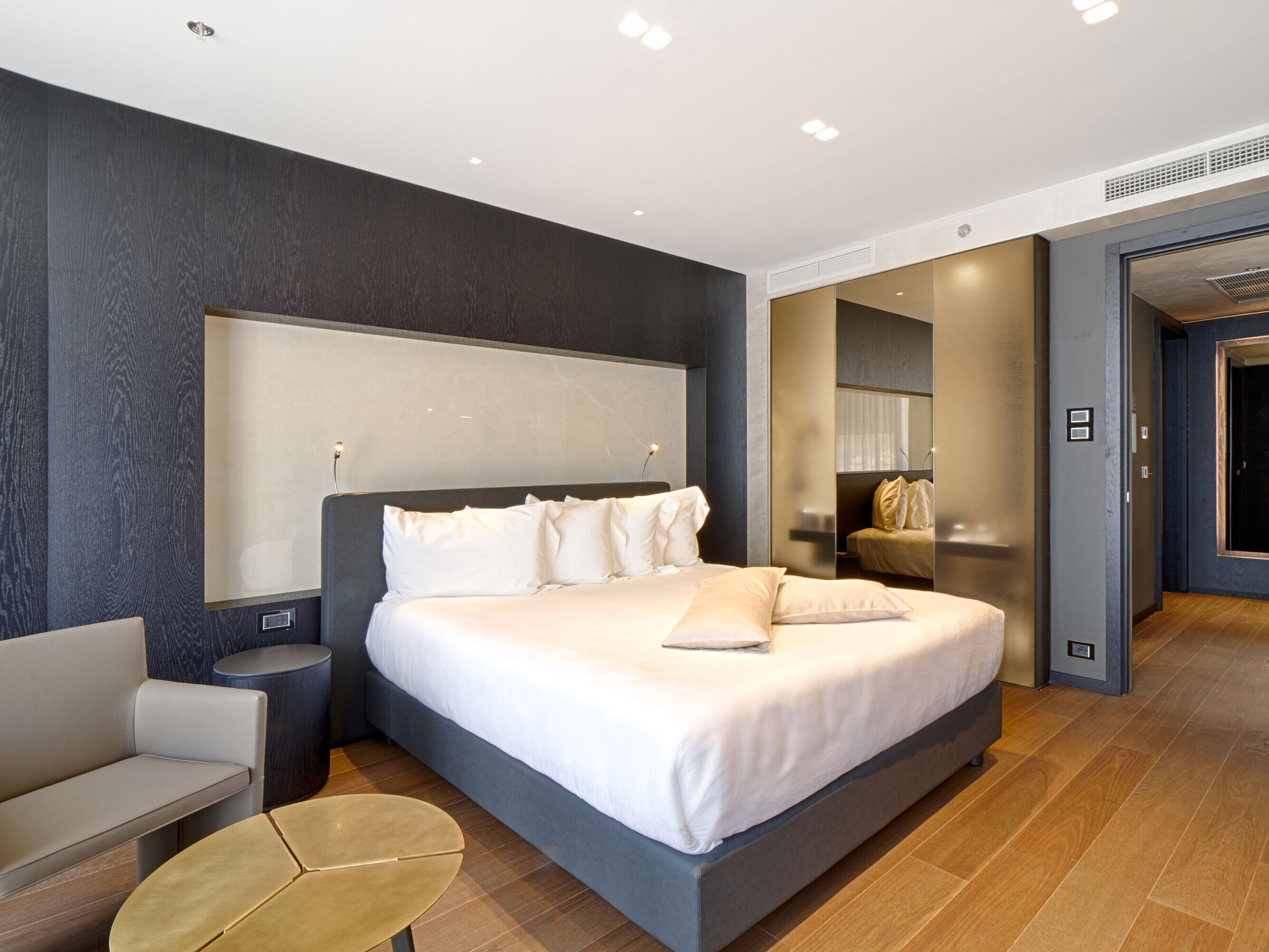 Modernes Hotelzimmer mit Kingsize-Bett, heller Wandnische und Holzfußboden im Maritim Hotel Plaza Tirana