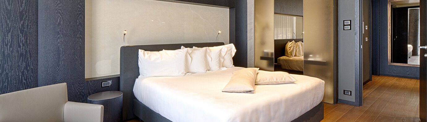 Modernes Hotelzimmer mit Kingsize-Bett, heller Wandnische und Holzfußboden im Maritim Hotel Plaza Tirana