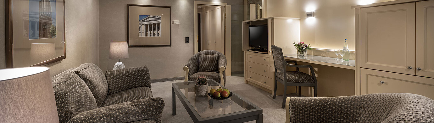 Elegante Suite im Maritim Hotel Darmstadt mit gemütlicher Sitzecke, stilvoller Beleuchtung und Schreibtisch.