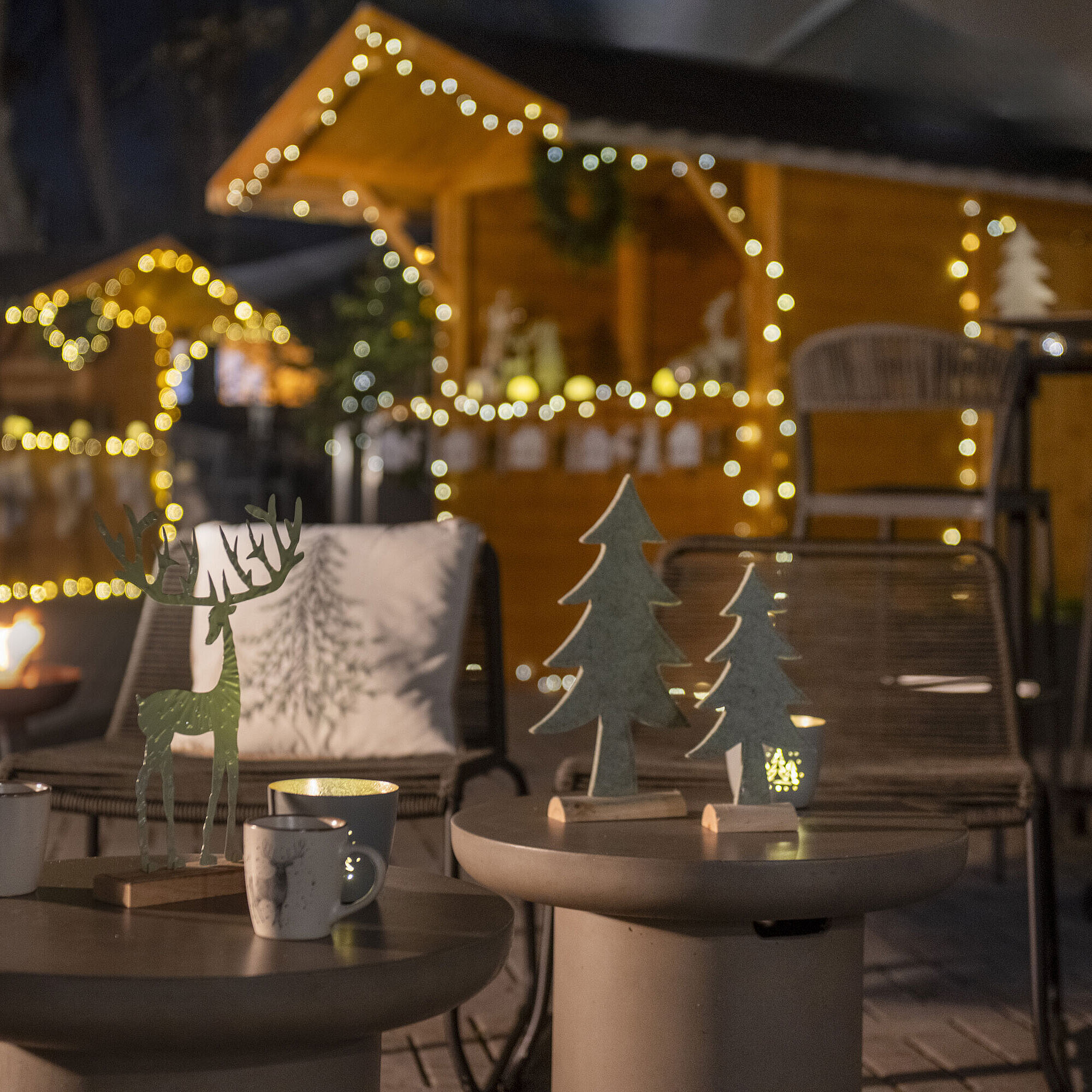 Weihnachtlich geschmückter Außenbereich des Maritim Hotels Darmstadt mit Lichterketten, Holzdekorationen und einem Feuerkorb.