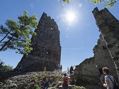 Die historische Burgruine Drachenfels in Königswinter mit Besuchern und strahlendem Sonnenschein.
