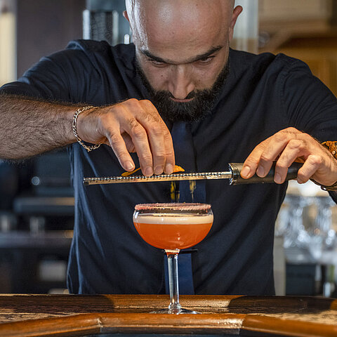 Barkeeper verfeinert einen Cocktail an der Bar des Maritim Hotel Würzburg.