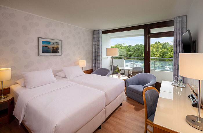 Classic Zimmer mit Doppelbett, Sitzecke, Schreibtisch und großem Fenster mit Blick ins Grüne