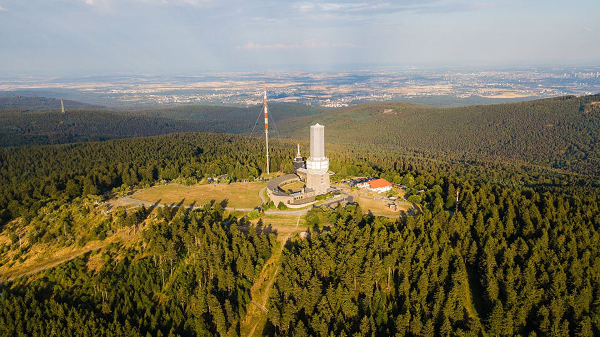 Luftaufnahme des Großen Feldbergs im Taunus mit Sendeturm, Waldlandschaft und Blick bis nach Frankfurt.