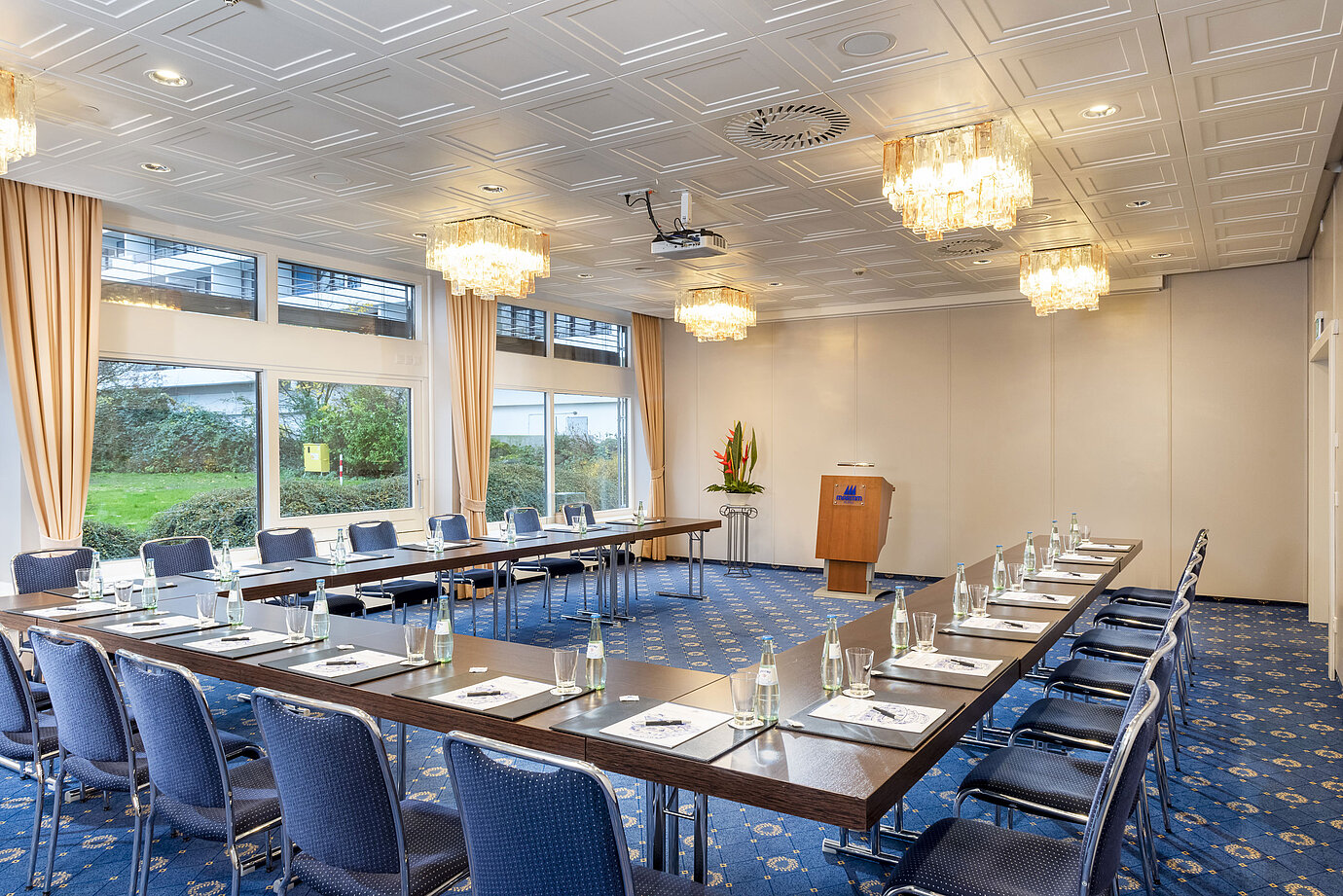 Der Salon Lübeck im Maritim Hotel Kiel, ein moderner Konferenzraum mit U-förmiger Bestuhlung, großen Fenstern und Kronleuchtern.