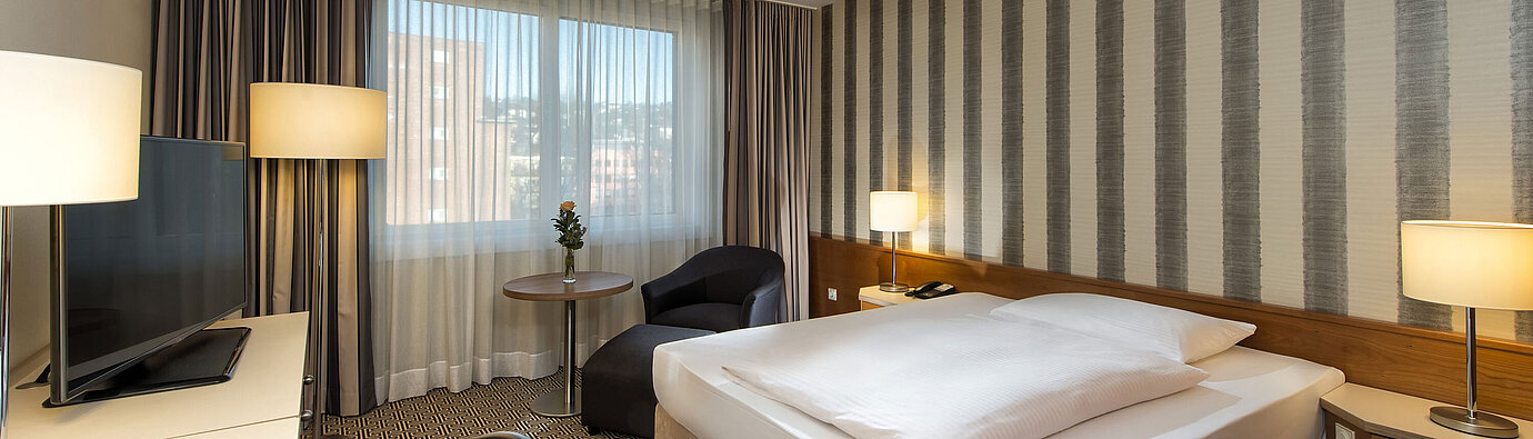 Modernes Einzelzimmer mit Schreibtisch, großem Fenster und Stadtblick im Maritim Hotel Stuttgart