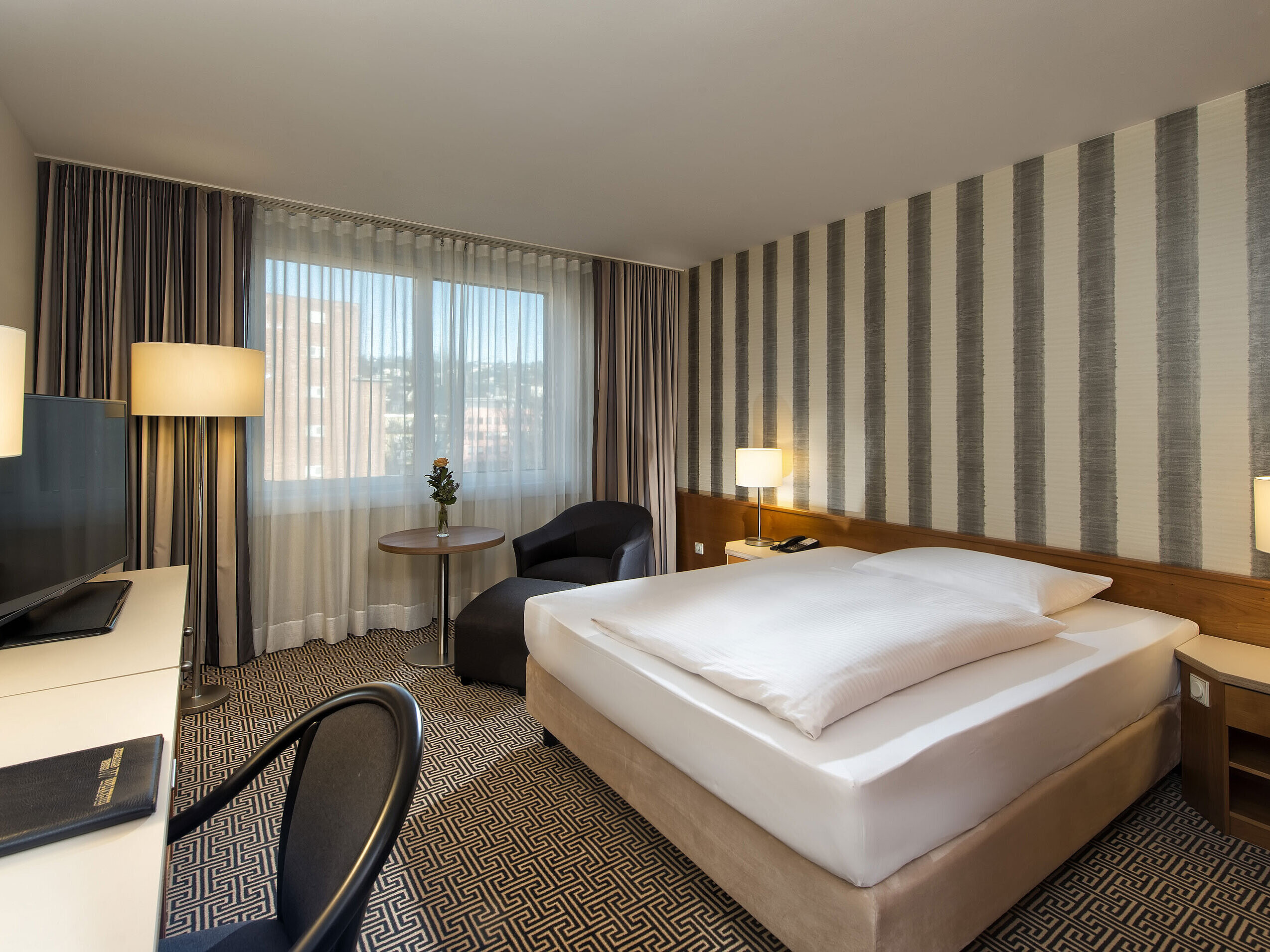 Modernes Einzelzimmer mit Schreibtisch, großem Fenster und Stadtblick im Maritim Hotel Stuttgart