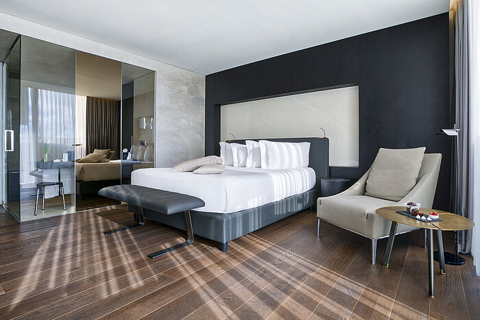 Modernes Hotelzimmer im Maritim Hotel Plaza Tirana mit Glastrennwand, Designmöbeln und Holzfußboden