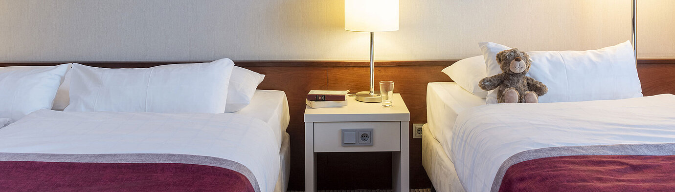 Classic Familienzimmer im Maritim Hotel Bonn mit zwei Betten, Nachttisch und moderner Kunst für einen komfortablen Aufenthalt