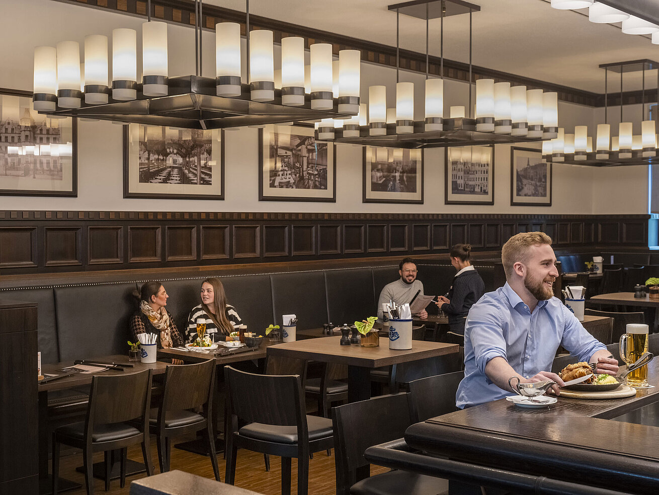Rheinische Stov Gäste genießen Speisen im gemütlichen Restaurant "Rheinische Stov" des Maritim Hotel Düsseldorf mit stilvollem Interieur.
