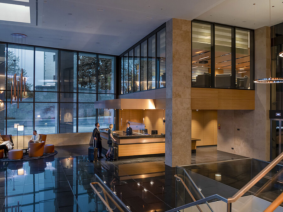 Die moderne Lobby des Maritim Hotel Ingolstadt mit hohen Glasfenstern, Rezeption und gemütlichen Sitzbereichen.