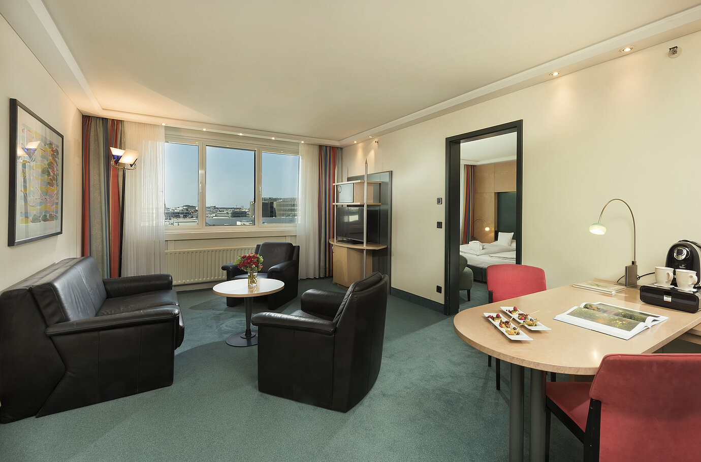Wohnzimmerbereich der Superior Suite im Maritim proArte Hotel Berlin mit Sitzbereich und Blick aus dem Fenster.