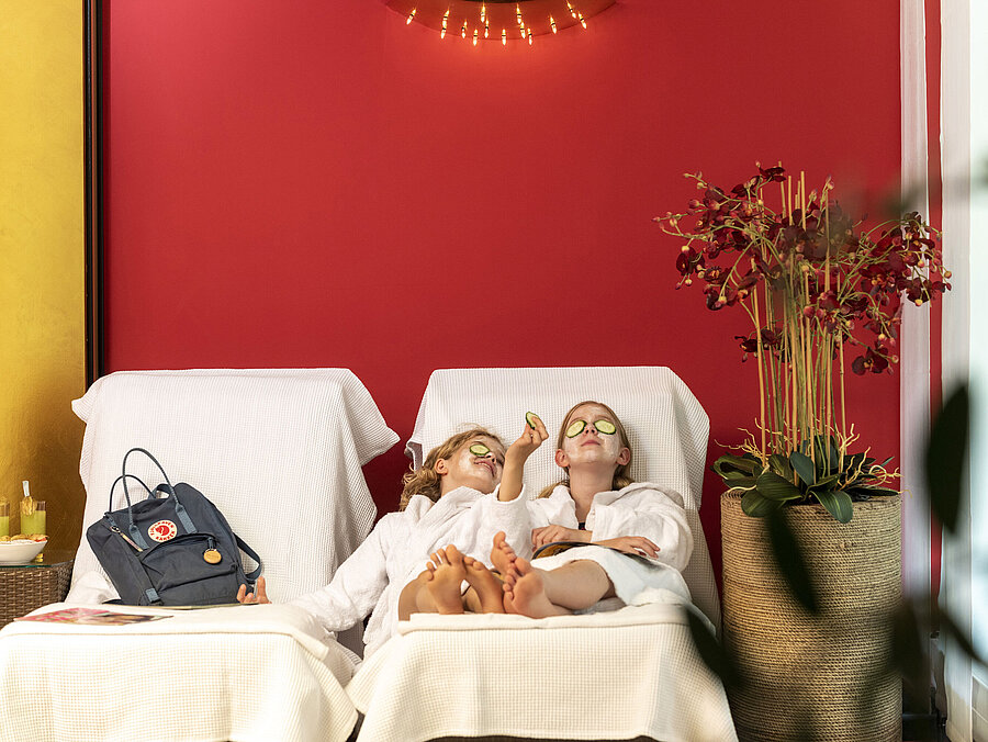 Zwei Mädchen mit Gesichtsmaske und Gurkenscheiben entspannen im Spa des Maritim Hotels und genießen ihre Behandlung.
