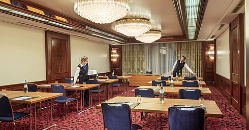 Salon Bonn, Servicemitarbeiter bereiten den Raum mit Tischen, Wasserflaschen und Gläsern für eine Veranstaltung vor.